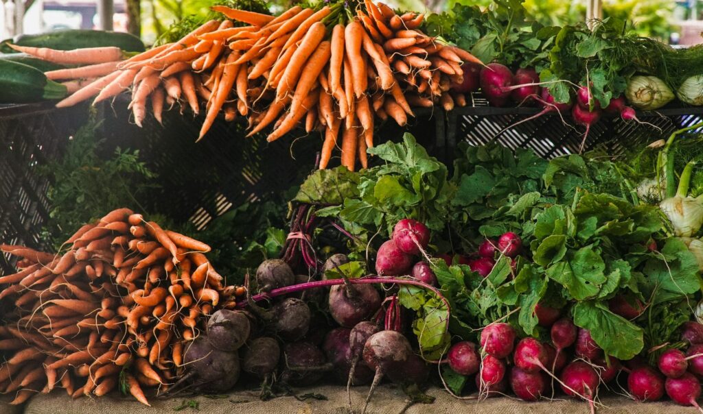 A vibrant display of fresh carrots, radishes, and greens at a local outdoor market.